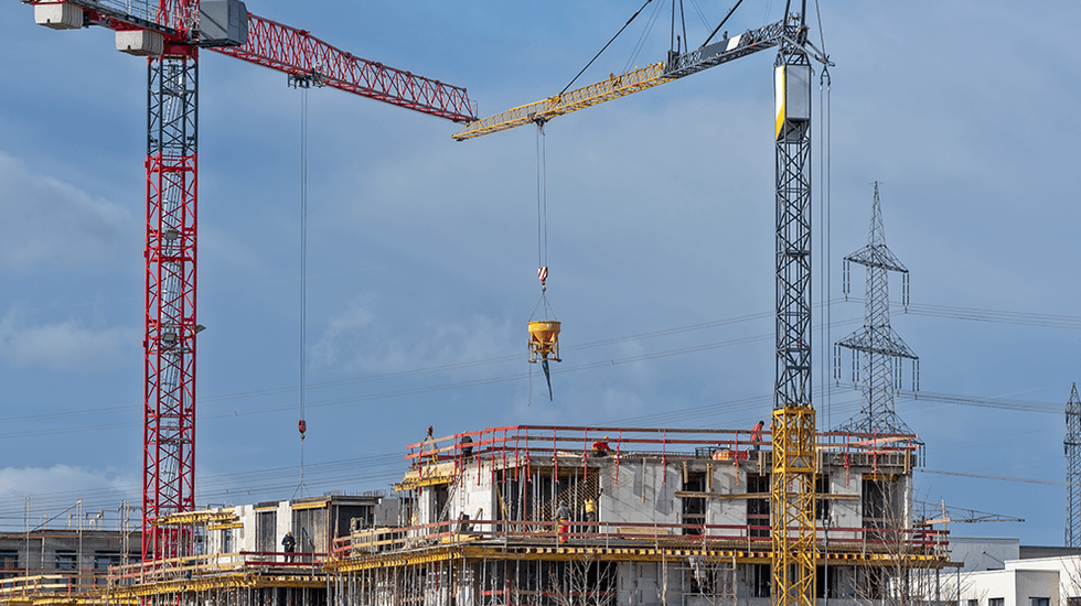 Baustelle mit zwei Kränen und blauer Himmel im Hintergrund